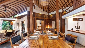 Un vaste espace dédié à la salle à manger, avec une longue table en bois dressée pour le repas, entourée de chaises en bois.