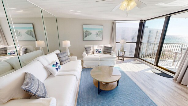 Un soggiorno moderno con un divano bianco, un tavolino rotondo e un balcone con vista sul mare.