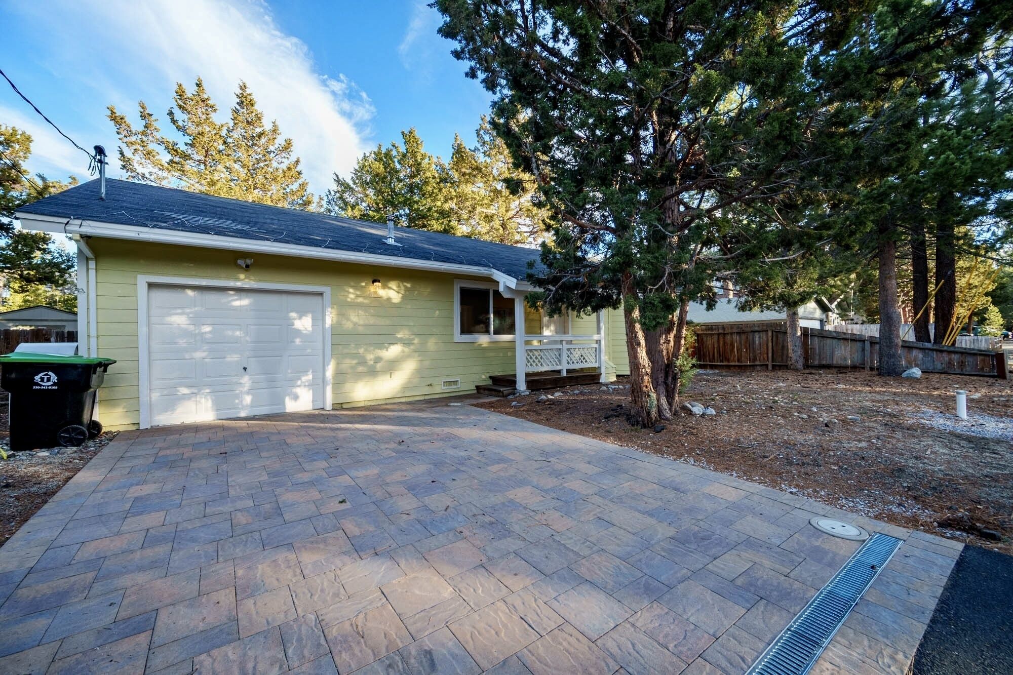 A single-story house with a garage, a covered porch, and a brick driveway.