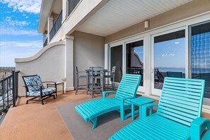 A balcony with turquoise lounge chairs, a small table, and a chair. - Seven Sandcastles 4 Bedroom Townhouse (Navarre)