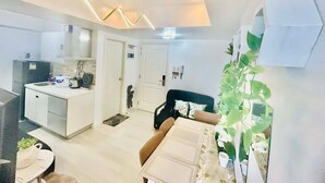 A modern apartment with a kitchen, dining area, and a living room. - Cozy Condos at Azure Urban Resort (Parañaque)