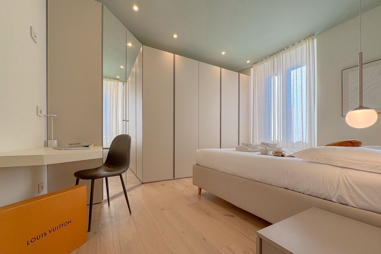 A modern bedroom with a bed, a desk, a chair, and a wardrobe.