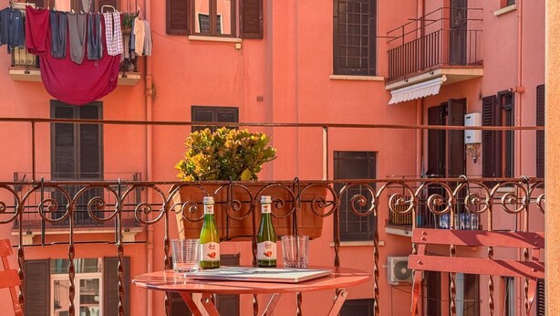 Ein Balkon mit Tisch, Flaschen, Gläsern und einem Blumentopf.