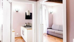 Een compacte leefruimte met een kitchenette, een bank en een televisie.