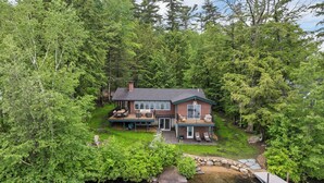Un chalet au bord du lac, doté d’une terrasse, de meubles de jardin et d’un quai.