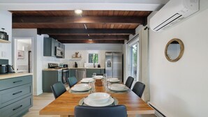 Una cocina moderna con vigas de madera, una mesa de comedor para cuatro personas y un ventanal grande.