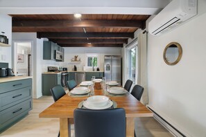 Una cocina moderna con vigas de madera, una mesa de comedor para cuatro personas y un ventanal grande.