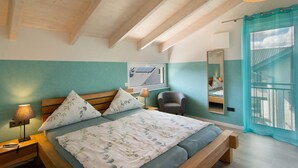 Une chambre à coucher comprenant un lit, une table de chevet, une lampe, une chaise, une fenêtre donnant sur un beau paysage et un miroir.