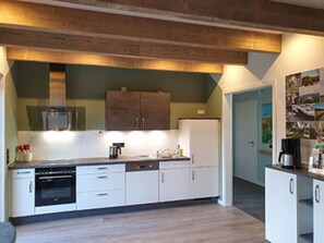 A modern kitchen with white cabinets, a dishwasher, an oven, and a coffee maker. - Holiday Home 'Ferienhaus Hofmeyer' with Private Terrace, Private Garden and Wi-Fi (Hofgeismar)