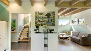 Un intérieur moderne comprenant un escalier, un coin cuisine et un espace salon avec un canapé et une table basse.