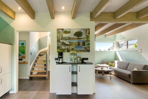 Un interior moderno con una escalera, una zona de cocina y un área de estar con un sofá y una mesa de centro.