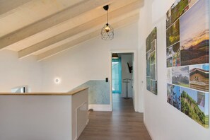 A hallway with wooden beams, a hanging light fixture, and a wall with multiple photographs. - Holiday Home 'Ferienhaus Hofmeyer' with Private Terrace, Private Garden and Wi-Fi (Hofgeismar)