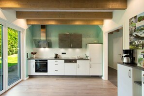A modern kitchen with a large window, built-in appliances, and a wooden ceiling. - Holiday Home 'Ferienhaus Hofmeyer' with Private Terrace, Private Garden and Wi-Fi (Hofgeismar)