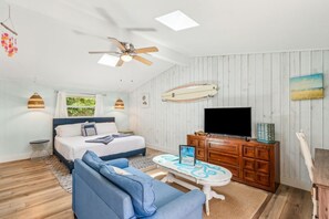 Ein Schlafzimmer mit einem Bett, einem Fernseher, einem Holzschrank und einem Deckenventilator.