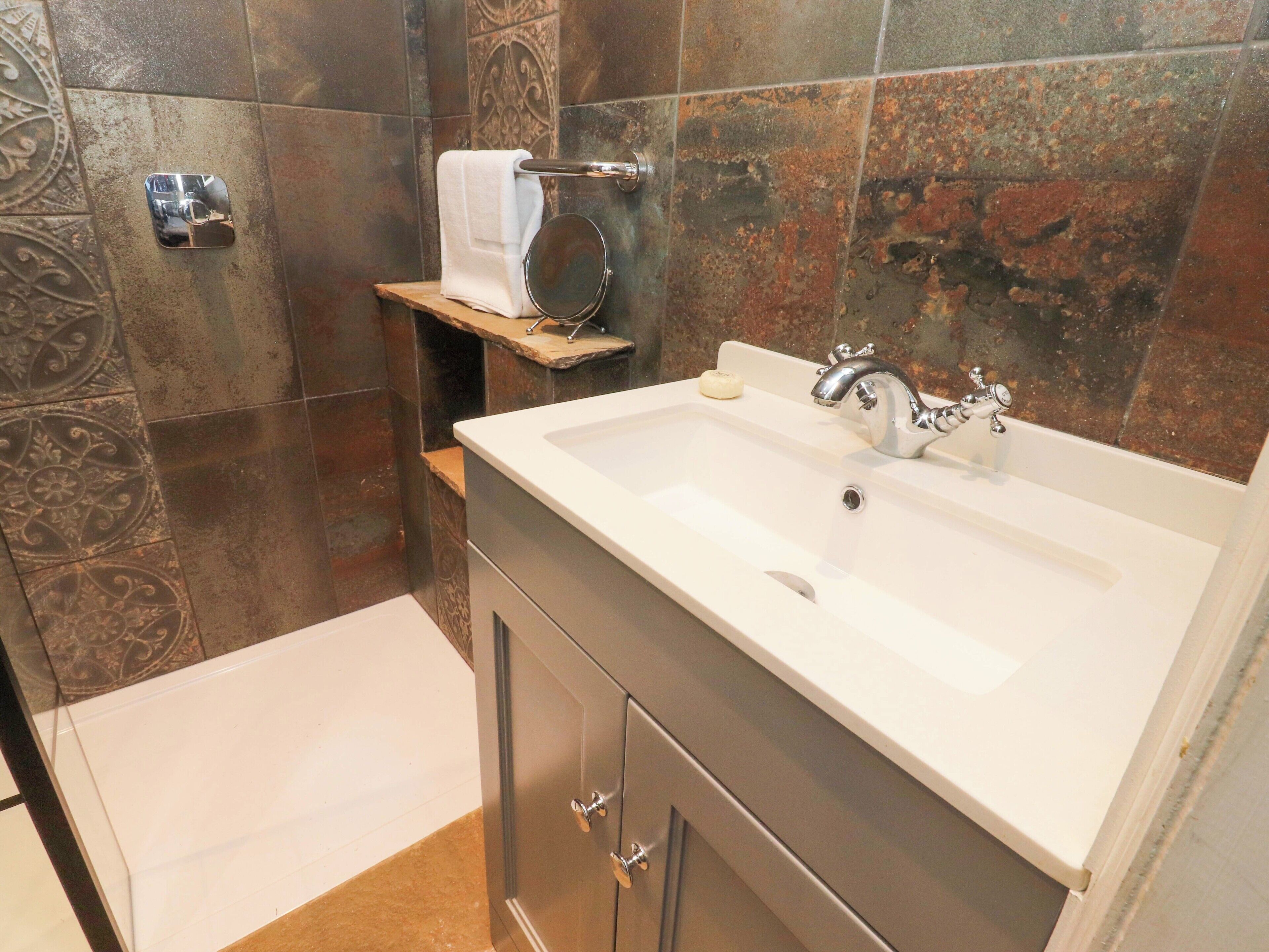 Un baño con un lavabo blanco, un espejo, un perchero para toallas y un jabonera.