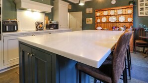 Una cocina amplia con una isla grande, muebles de cocina blancos y una pared de exhibición de platos de madera.