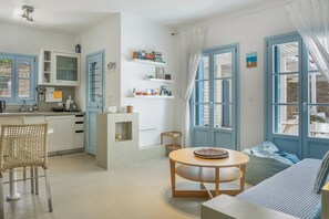 Eine moderne Küche mit blauen Schränken, ein Essbereich mit einem runden Tisch und eine gemütliche Sitzecke mit einer Couch und einem Sitzsack.