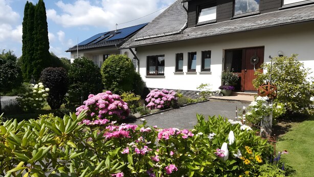 A house with solar panels, a well-maintained garden with various plants and flowers, and a neatly paved driveway. - Apartment Ingrid Alfes, Apartment 1 (Lennestadt-Halberbracht)