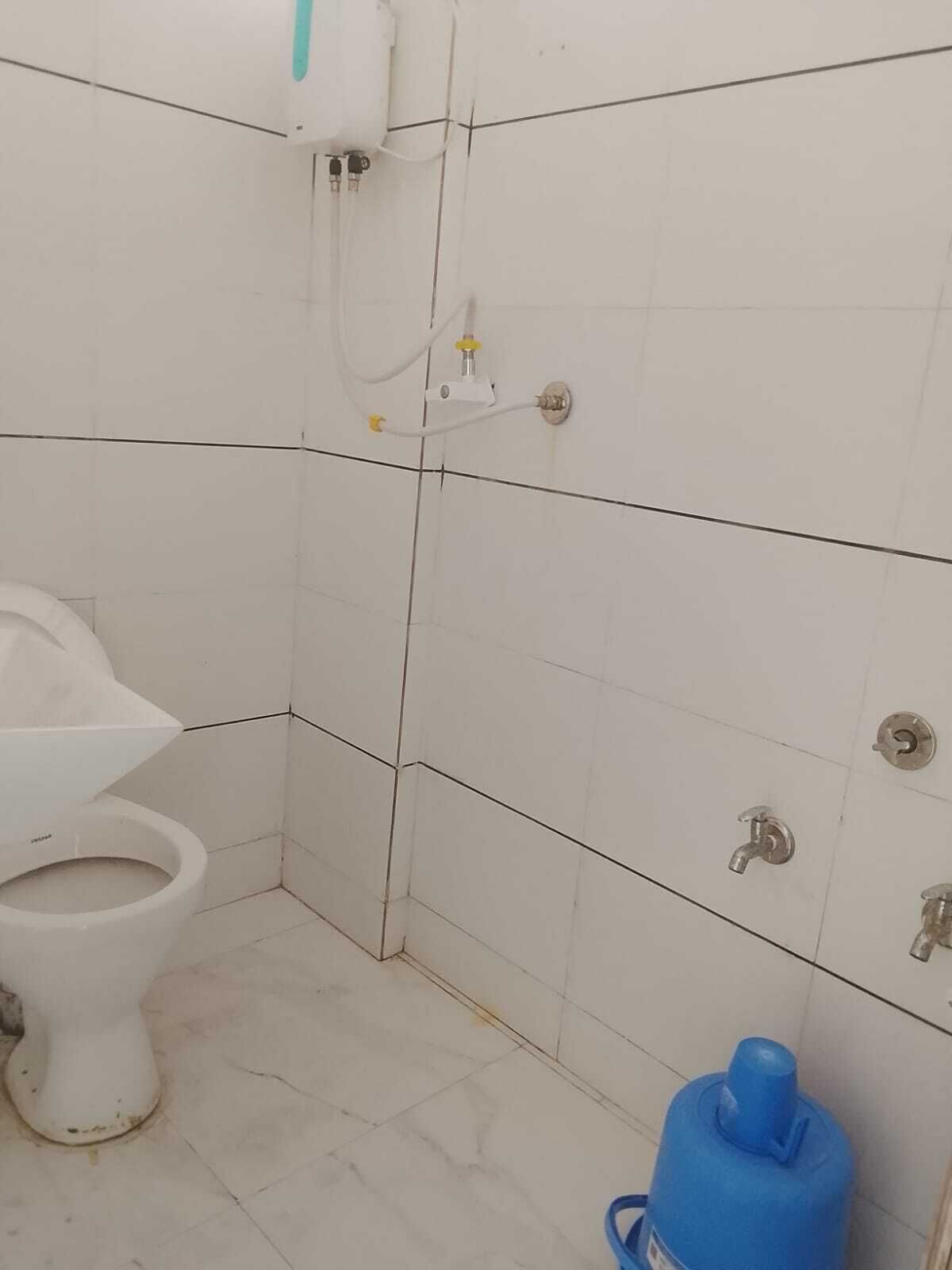 A small bathroom with a toilet, a shower, and a water heater.