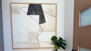 Una consola negra con un cuenco blanco, una planta en maceta y un cuadro abstracto enmarcado en la pared.
