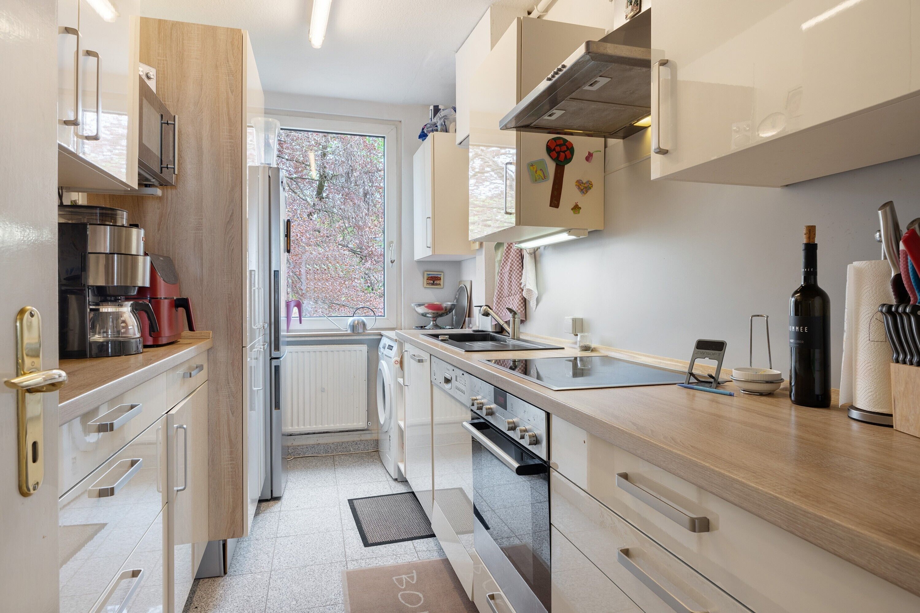 Eine moderne Küche mit Edelstahlgeräten, Holzschränken und Blick ins Freie.
