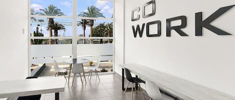 A modern office space with a large window, a 'DO WORK' sign, and a view of palm trees and buildings.