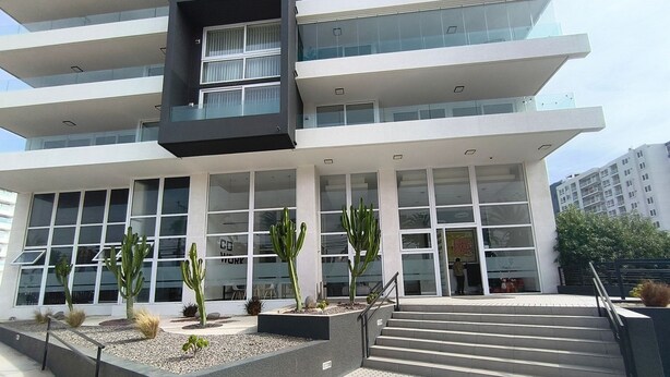 A modern building with multiple floors, large windows, and a staircase leading to the entrance. - Oceana Suites Puerto Serena (La Serena)