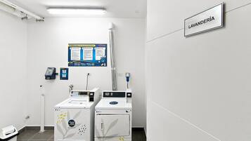 Un cuarto de lavandería con dos lavadoras, un letrero en la pared que indica la sala y un cartel con instrucciones.