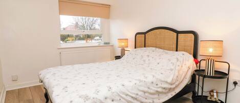 A bedroom with a bed, a window with a view, two bedside lamps, and a radiator.