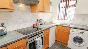 A modern kitchen with wooden cabinets, a Bosch dishwasher, a Bosch washing machine, and a gas stove. - Poole Quay Cottage (Poole)