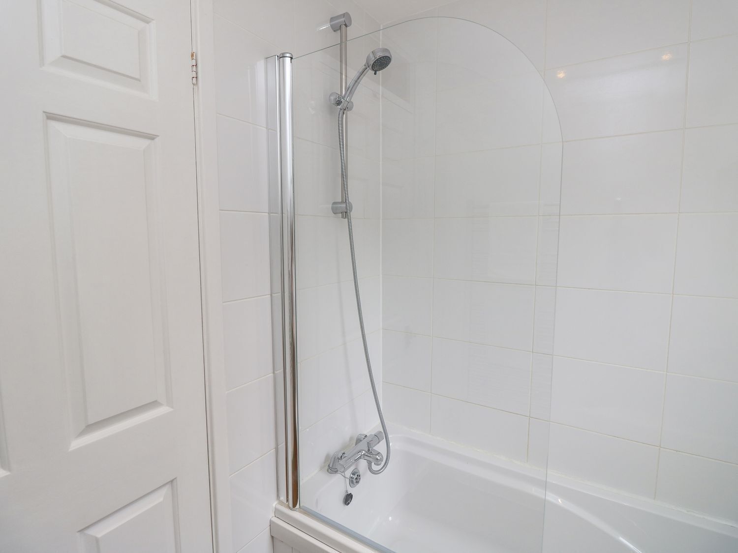 A modern shower enclosure with a glass door, a handheld showerhead, and a handheld shower attachment.