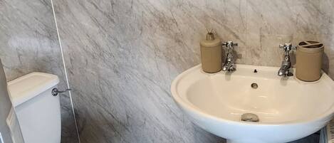 Ein Badezimmer mit Waschbecken, zwei Seifenspendern, Toilette und Duschbereich.