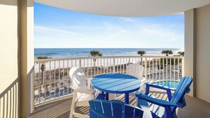 A balcony with a view of the beach and ocean, featuring a round table and blue chairs. - Tradewinds 202 by Liquid Life (Orange Beach)
