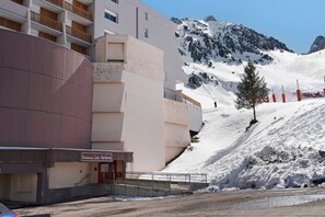 Un hôtel au design moderne, avec une piste de ski en arrière-plan et un ciel dégagé.