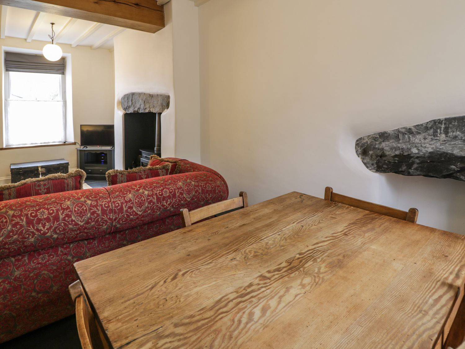 Una sala de estar acogedora con una mesa de madera y un sofá rojo estampado.