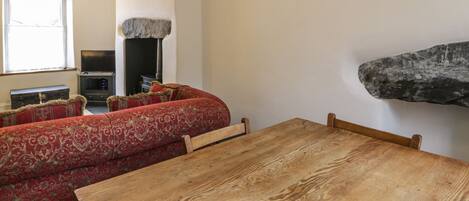 Una sala de estar acogedora con una mesa de madera y un sofá rojo estampado.