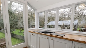 A kitchen with a large window, a sink, and cabinets. - Peniel Cottage (Caernarfon)