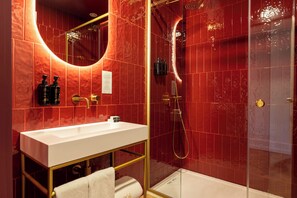 A modern bathroom with a white sink, gold fixtures, and red tiled walls. - 1904 Benfica Hotel FLH Hotels (Lisbon)