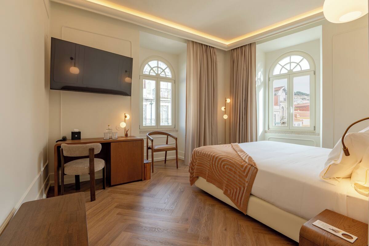 Ein Hotelzimmer mit Bett, Schreibtisch, Stuhl und großen Fenstern.