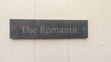 A metal plaque with the inscription "The Romantic" mounted on a white wall.