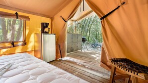 A tent with a bed, a coffee maker, and a storage cabinet. - Glamping “Safari Tent” Air Conditioning Available Shared Pool (Calviac-en-Périgord)