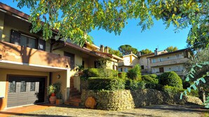 A residential building with a stone wall, potted plants, and a clear blue sky. - Casa Alce (Arezzo)