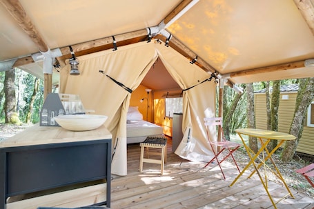 A tent with a bed, a table, and a chair inside.