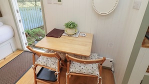 A small dining area with a wooden table, two chairs, a potted plant, and a wall-mounted mirror. - Woodland (Hexham)