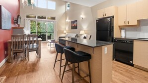 Una cocina moderna con una isla central, taburetes de bar, un refrigerador negro y armarios de madera.