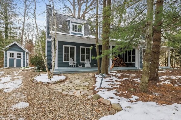 A two-story house with a stone pathway leading to a porch with outdoor seating.