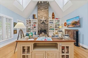 A room with a stone fireplace, wooden shelves with various items, a wooden counter, and a painting on the wall.