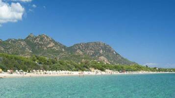 Uma praia com águas turquesa cristalinas e montanhas ao fundo.
