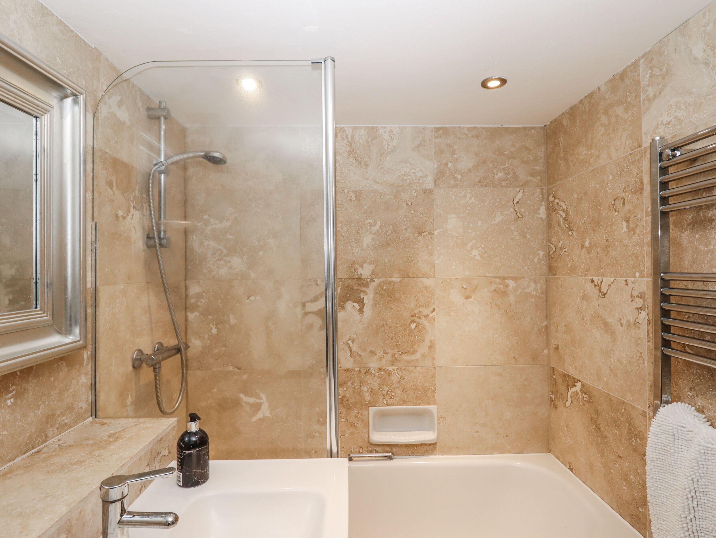 A bathroom with a glass-enclosed shower, a bathtub, and a vanity with a mirror.