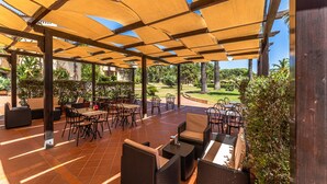Eine Außenpatio mit Korbmöbeln und einer Holzpergola, die Schatten spendet.
